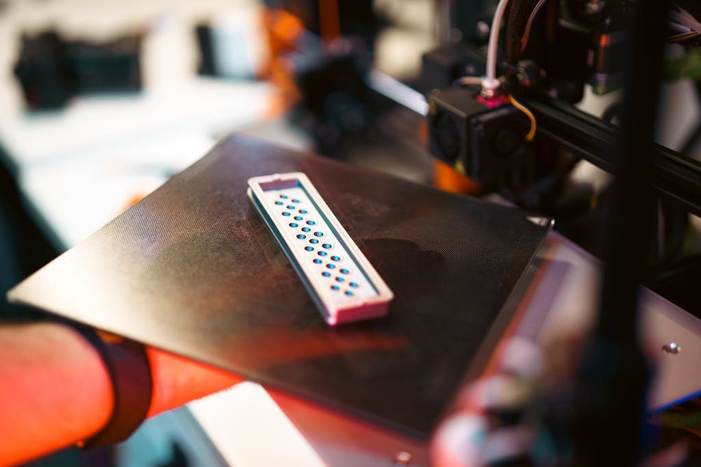 Close-up of a 3D printed part on an industrial printer in a workshop setting.